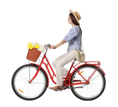 Şapkalı gülümseyen kadın beyaz arka planda bir sepet çiçekle bisiklet sürüyor.