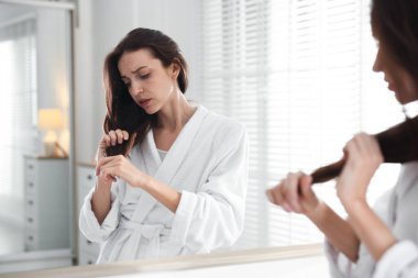 Saç dökülme sorunu olan kadın aynaya bakıyor.