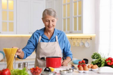 Mutfaktaki masada yemek pişiren son sınıf kadını.