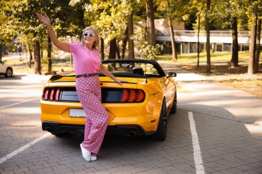 Modern Cabriolet yakınlarında güneş gözlüklü şık bir son sınıf öğrencisi.