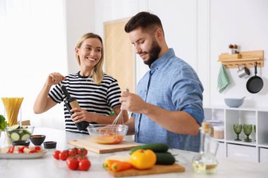 Gülümseyen kadın mutfakta kocasıyla yemek pişirirken şarap şişesini açıyor.