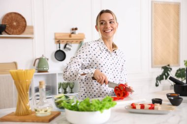 Yemek pişirme süreci. Mutfakta masada biber kesen gülümseyen kadın.