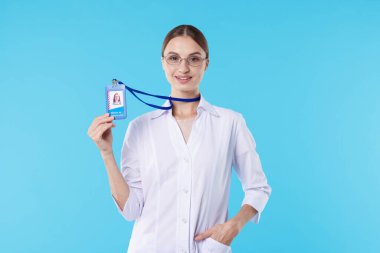 Açık mavi arka planda rozeti olan profesyonel hemşire.