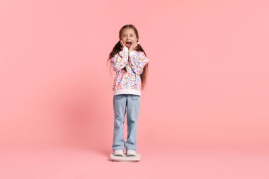 Pembe arka planda duran küçük kız