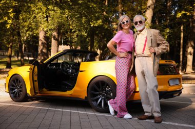 Modern Cabriolet yakınlarında güneş gözlüklü şık bir çift.