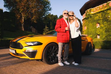 Modern Cabriolet yakınlarında güneş gözlüklü şık bir çift.