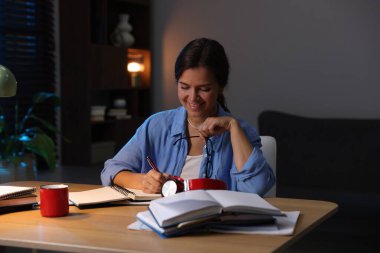 Ahşap masada sınava hazırlanan mutlu öğrenci.