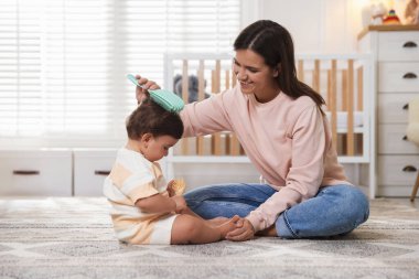 Anne evde bebeğinin saçını tarıyor.