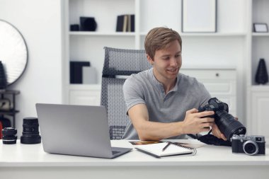 Stüdyoda beyaz masada çalışan profesyonel fotoğrafçı.