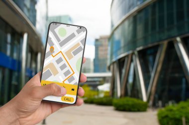 Şehir caddesinde taksi çağırmak için cep telefonu uygulaması kullanan bir adam.