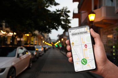 Şehir caddesinde taksi çağırmak için cep telefonu uygulaması kullanan bir adam.