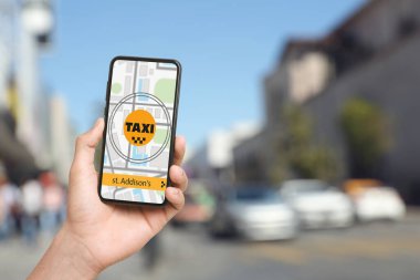 Şehir caddesinde taksi çağırmak için cep telefonu uygulaması kullanan bir adam.