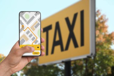 Şehir caddesinde taksi çağırmak için cep telefonu uygulaması kullanan bir adam.