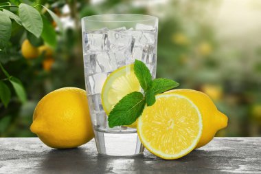 Bulanık yeşil arka planda limonlu su ve buzlu cam.