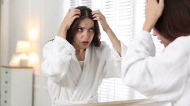 Saç dökülme sorunu olan kadın aynaya bakıyor.