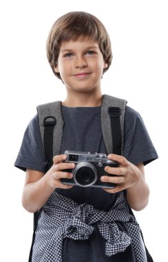 Meslek seçimi. Kameralı ve sırt çantalı küçük çocuk beyaz arka planda fotoğrafçı gibi davranıyor.