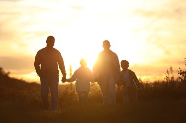 Aile gün batımında el ele tutuşuyor.