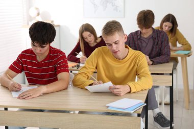 Ahşap masada sınava giren öğrenciler