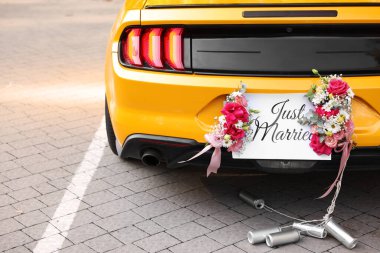 Düğün arabası. Cabriolet sadece evlilik kartıyla dekore edilmiş, güzel çiçekler ve teneke kutular, yakın plan.