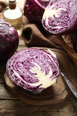 Fresh ripe red cabbages and knife on wooden table, closeup