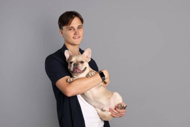 Gri arka planda sevimli Fransız bulldog 'unu tutan adam. Metin için boşluk