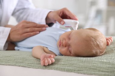 Çocuk doktoru küçük çocuğu kızılötesi termometreyle hastanede muayene ediyor, yakın plan. Bebeğin sağlığını kontrol ediyorum.