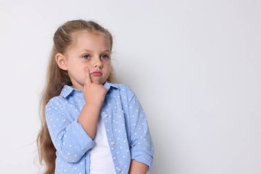 Açık gri arka planda düşünceli küçük bir kız. Metin için boşluk