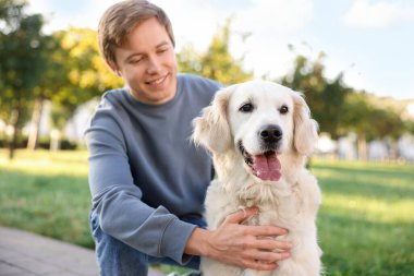 Parkta sevimli golden retriever köpeği olan adam.