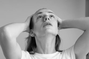 Gri arka planda ağlayan bir kadın, yakın plan. Siyah ve beyaz etkisi