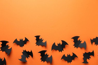 Cadılar Bayramı dekoru. Siyah kağıt yarasalar turuncu arka planda, düz yerde. Metin için boşluk