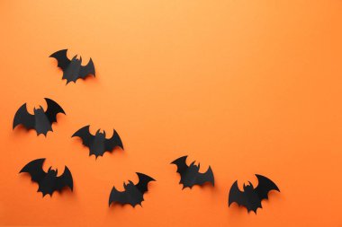 Cadılar Bayramı dekoru. Siyah kağıt yarasalar turuncu arka planda, düz yerde. Metin için boşluk