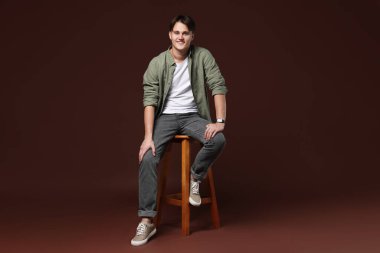 Kahverengi arka planda, kotlu şık bir adam.