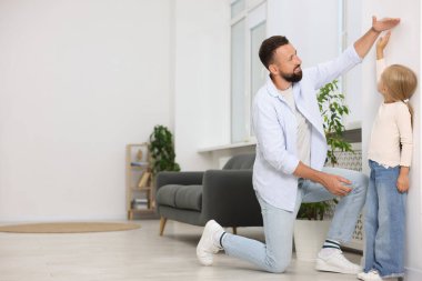 Babası evdeki beyaz bir duvarın yanında küçük kızının boyunu ölçüyordu. Metin için boşluk