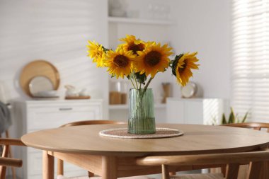Beautiful sunflowers in vase on dining table at home