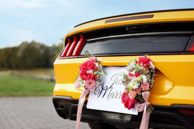 Düğün arabası. Cabriolet dekore edilmiş. Sadece evlilik kartı ve açık havada güzel çiçekler, yakın plan.