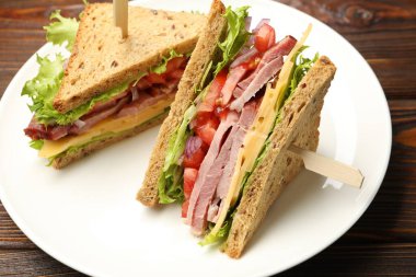 Delicious sandwiches with ham, cheese and vegetables on wooden table, closeup