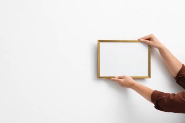 Beyaz duvara boş bir diploma çerçevesi asan kadın, yakın plan. Tasarım için model