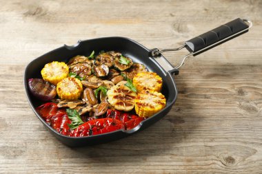 Ahşap masada nefis ızgara sebzeler, mantarlar ve maydanozlar.