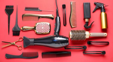 Different hair styling tools on red background, flat lay