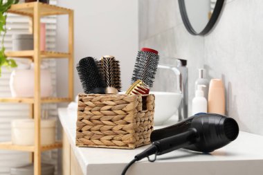 Tuvaletteki beyaz masada farklı saç şekillendirme aletleri.