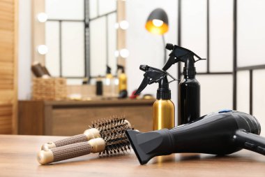 Kuafördeki ahşap masada farklı saç şekillendirme araçları, yakın plan.