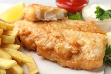 British Traditional Fish and chips served with sauces on table, closeup