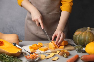 Gri masada balkabağı kesen kadın, yakın plan.