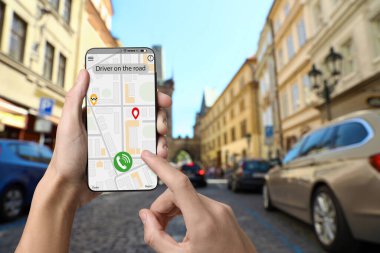 Şehir caddesinde taksi çağırmak için cep telefonu uygulaması kullanan bir adam.