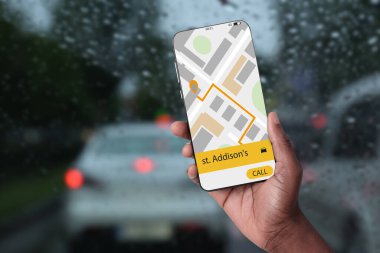Yağmurlu havalarda taksi çağırmak için cep telefonundaki uygulamayı kullanan adam, yakın plan.