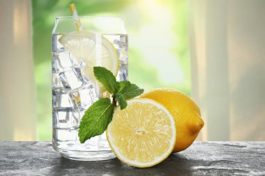 Limonlu su ve buzlu cam küpler masanın üzerinde, pencereye karşı.