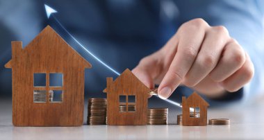 Zenginlik kavramı. Bozuk para istifleyen adam, yakın plan. Masadaki evin modelleri.