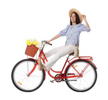 Şapkalı gülümseyen kadın beyaz arka planda bir sepet çiçekle bisiklet sürüyor.