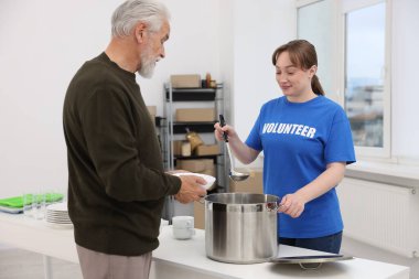 Yaşlılar için insani yardım. Gönüllü içeride kıdemli bir adama yemek veriyor.