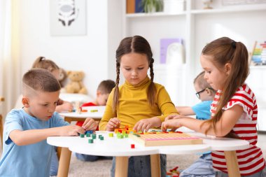 İlkokulda ders sırasında beyaz masalarda oturan sevimli çocuklar.